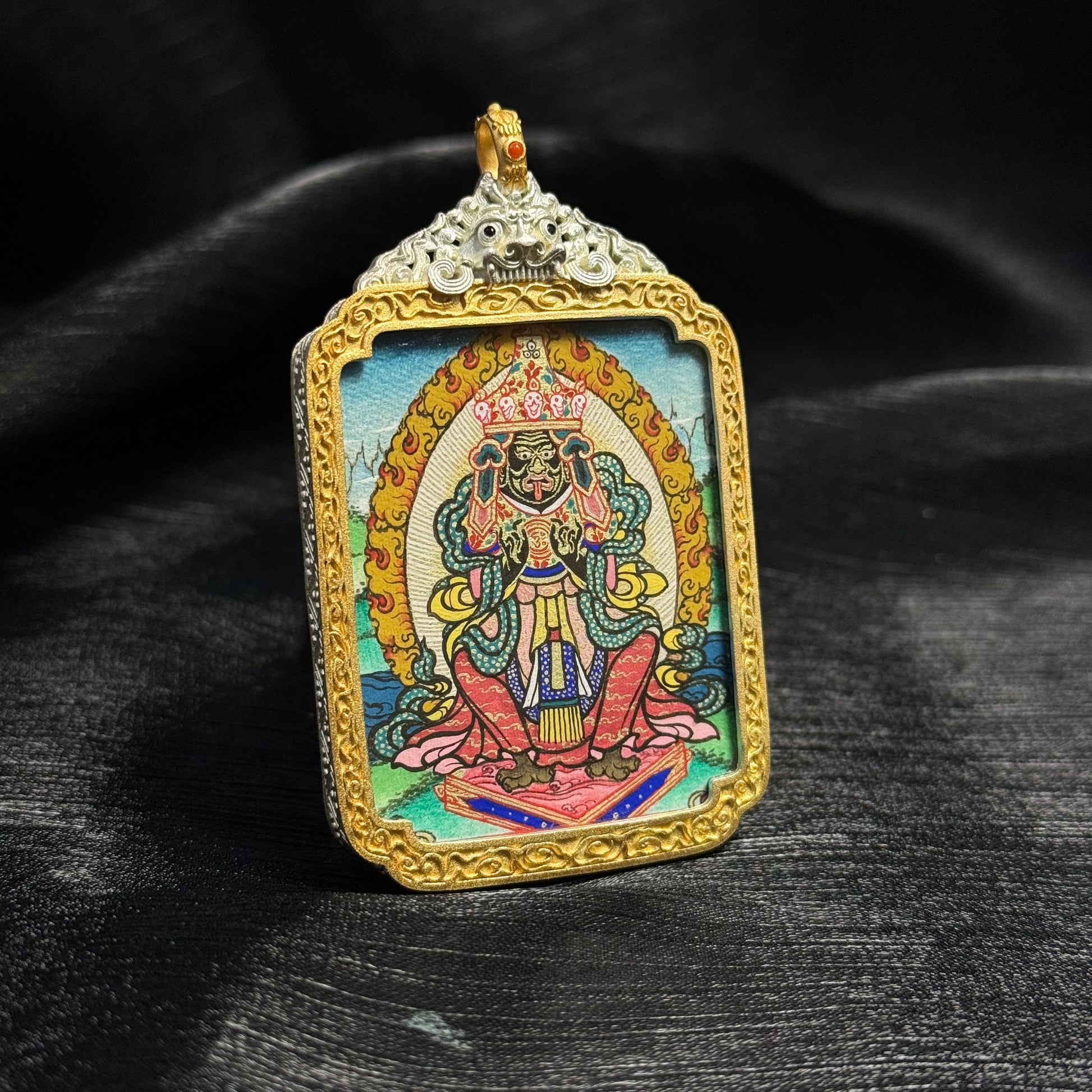 Detailed view of Zaki Lhamo Rebgong mini thangka pendant showing vivid mineral pigment colors, traditional Tibetan composition, and smooth thangka linework.