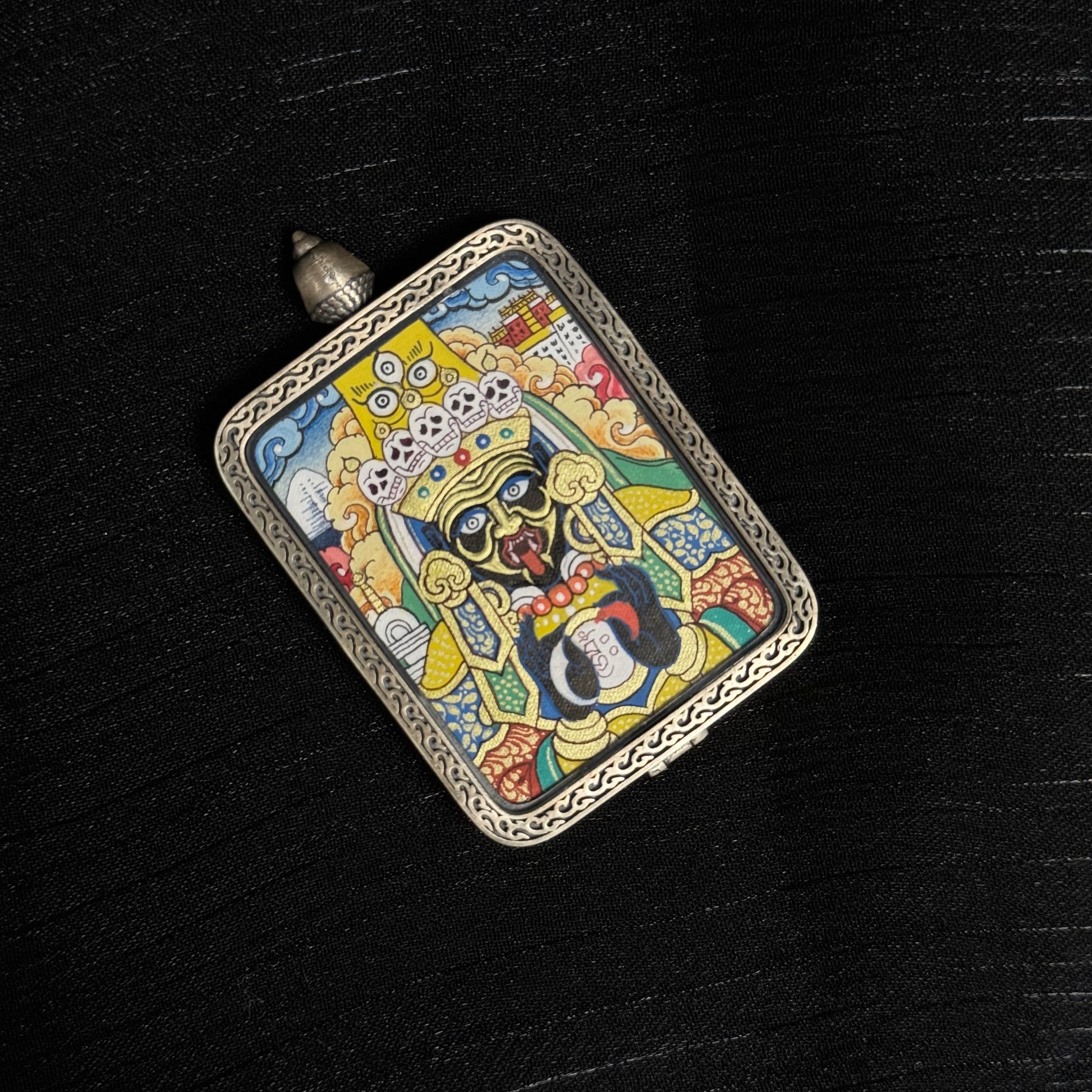 Top perspective of Zaki Lhamo mini thangka pendant showing the pendant loop, decorative silver frame, and vibrant mineral pigment painting of the Tibetan protective goddess.