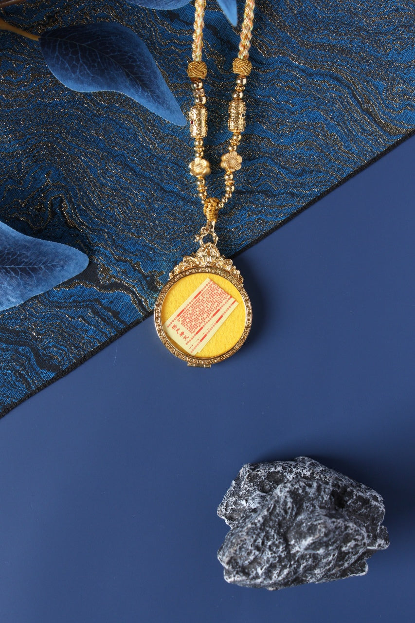 Back view of Zaki Lhamo mini thangka pendant showing round jewelry-grade titanium steel case construction and secure pendant setting