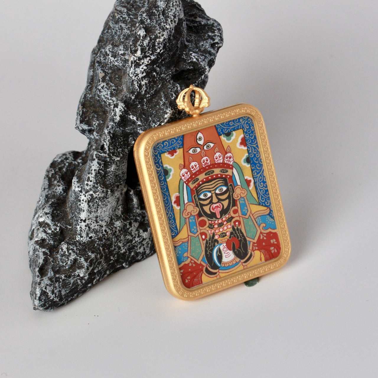 Close-up view of the Zaki Lhamo mini thangka pendant focusing on facial features, symbolic elements, and mineral pigment color layering.