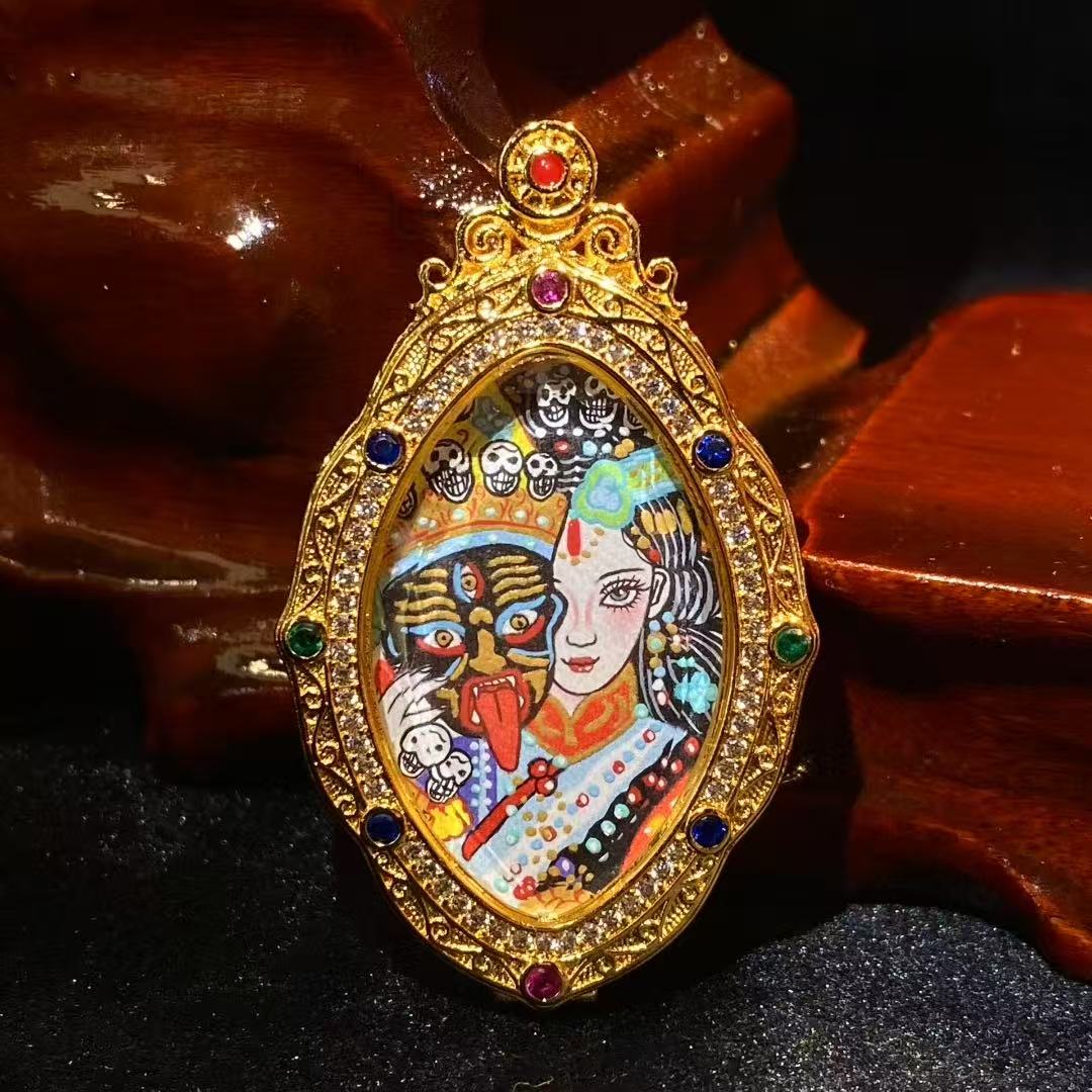Front view of a hand-painted Zaki Lhamo thangka pendant showing a dual-aspect composition within a sculpted copper gau box with a distinctive tapered oval shape