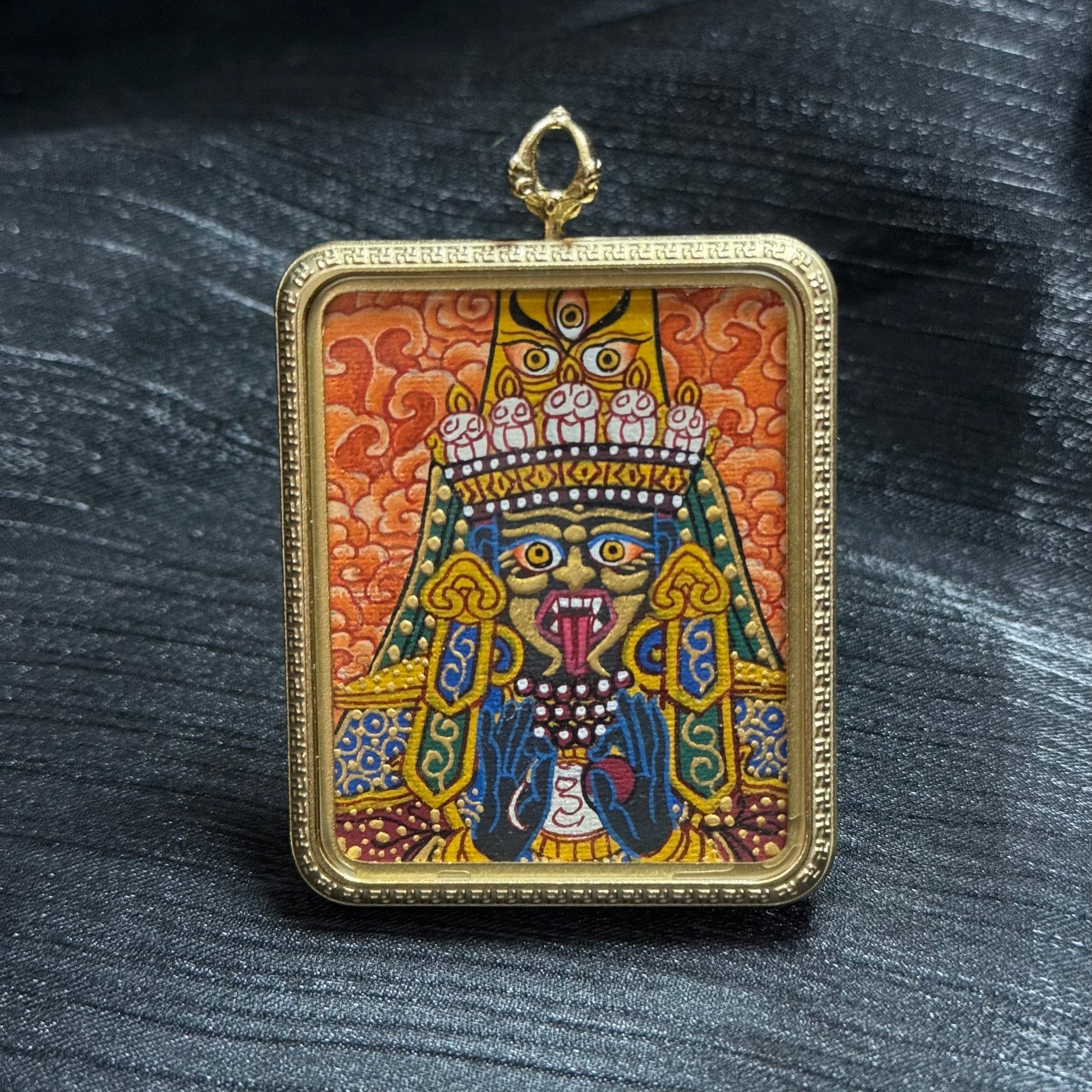 Close front detail of Zaki Ram protector goddess mini thangka pendant with colorful mineral pigments and ornate gold-tone frame