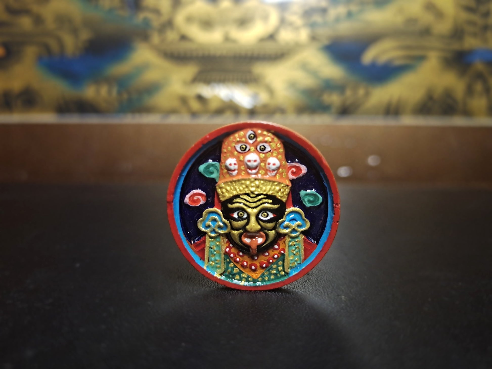 Close-up of Zaki Ram clay tsa-tsa sculpture showing detailed mineral pigment painting and three-dimensional relief features