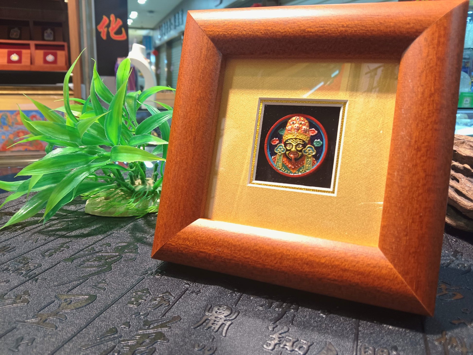 Angled view of Zaki Ram framed tsa-tsa thangka display mounted in Indonesian cypress wood frame suitable for altar or desk shrine