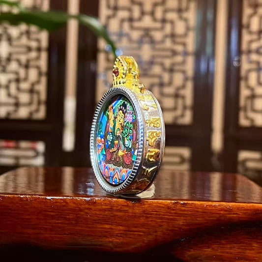 Side view of a hand-painted Manjushri Bodhisattva mini thangka pendant showing the circular 925 sterling silver Gau box frame