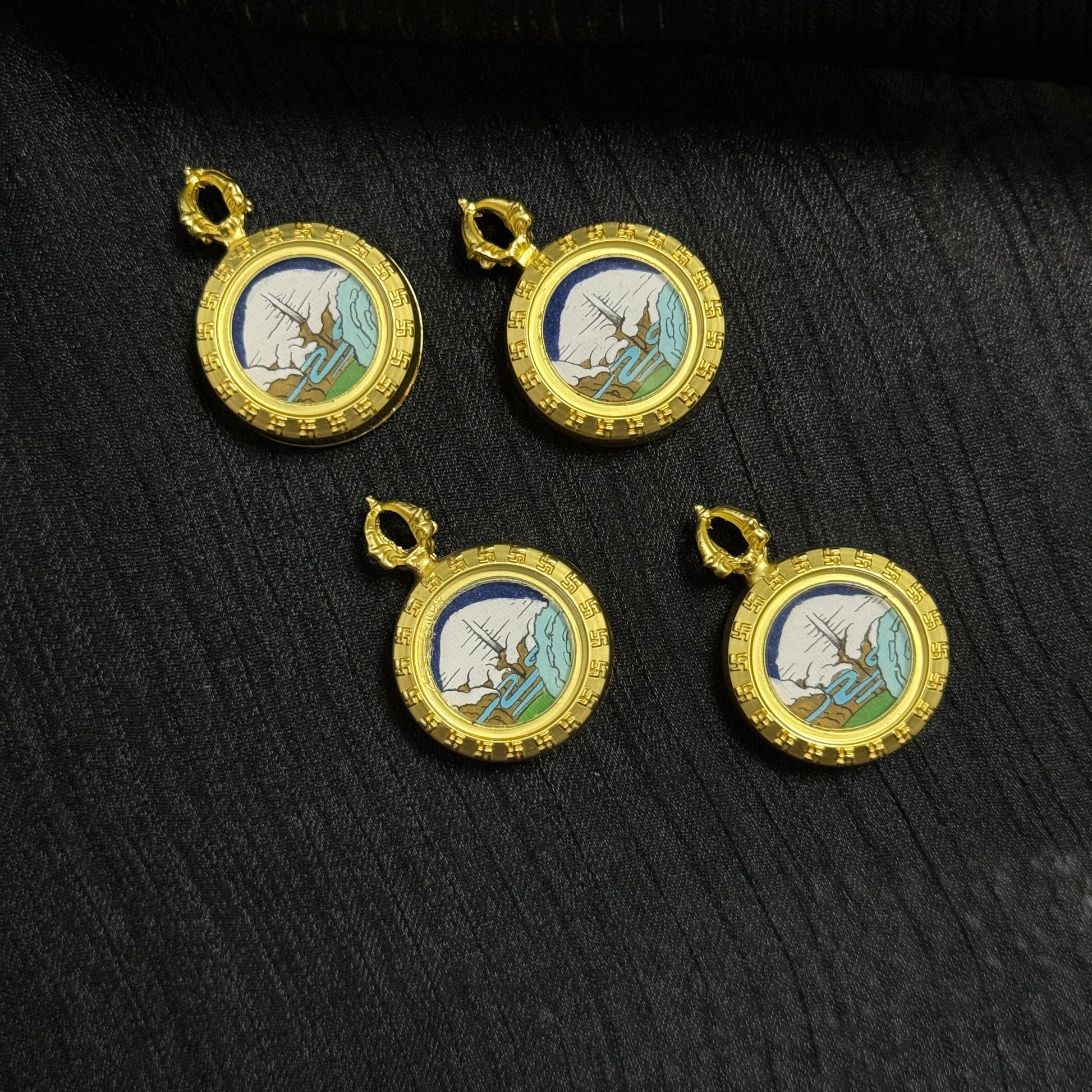 Multiple Mount Kailash Golden Summit mini thangka pendants arranged on fabric background, Rebgong hand-painted sacred mountain miniature thangka jewelry