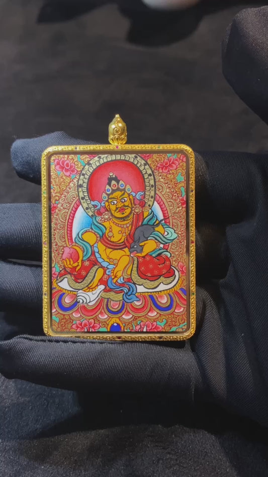 Close-up video of a large double-sided Tibetan Thangka pendant featuring Zaki Lhamo and Yellow Jambhala, fully hand-painted in 18K gold with full-detail Rebgong craftsmanship, set in a sapphire crystal Gawu box