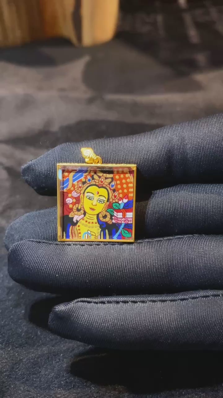 video of a double-sided Manjushri Bodhisattva mini thangka pendant, hand-painted and set in an 18K gold Gau box with sapphire crystal glass