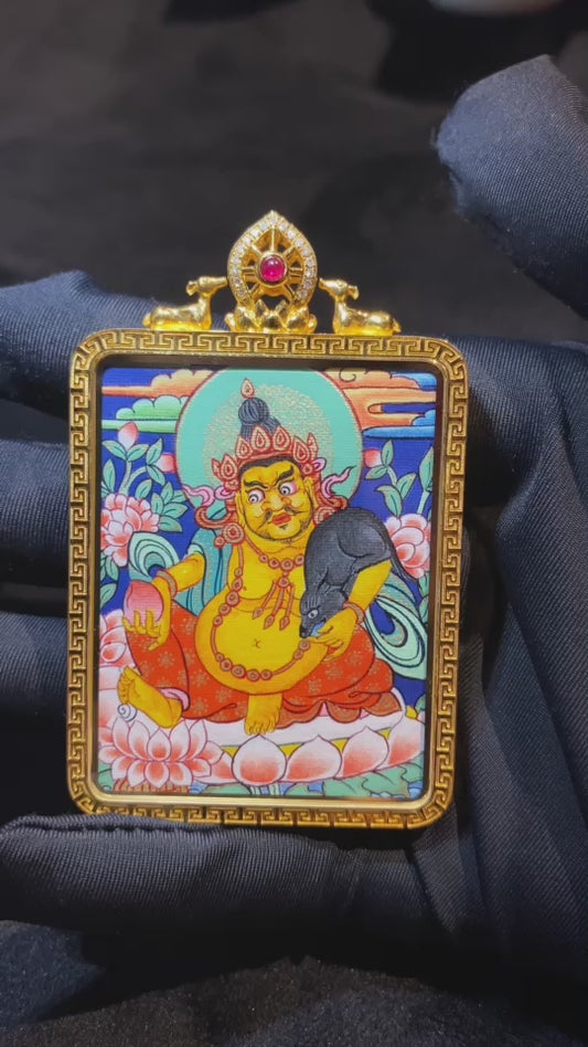 Close-up video of a double-sided Tibetan thangka pendant featuring Manjushri Bodhisattva and Yellow Jambhala, fully hand-painted with 18K gold in the Rebgong tradition and set in an 18K gold gau box with sapphire crystal mirror, symbolizing wisdom, learning, and balanced prosperity
