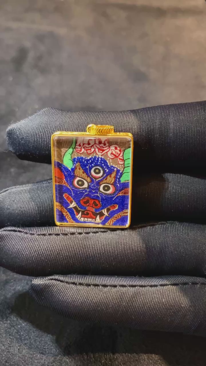 Close-up video of 18K gold double-sided hand-painted Yamantaka thangka pendant, showing Rebgong details, Gau box design, sapphire crystal, and protector symbolism