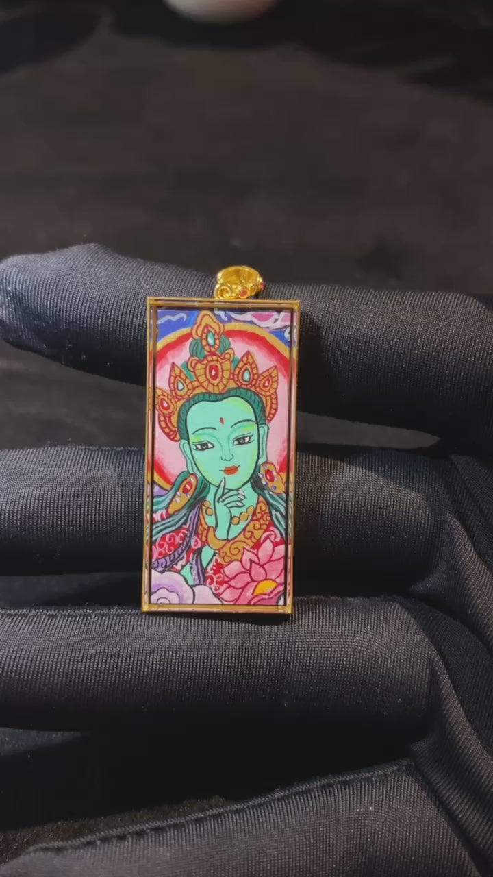 Product video showcasing a double-sided Green Tara and Om Mani Padme Hum Thangka pendant, fully hand-painted with 18K gold in Rebgong tradition and set in a sapphire crystal Gau box.
