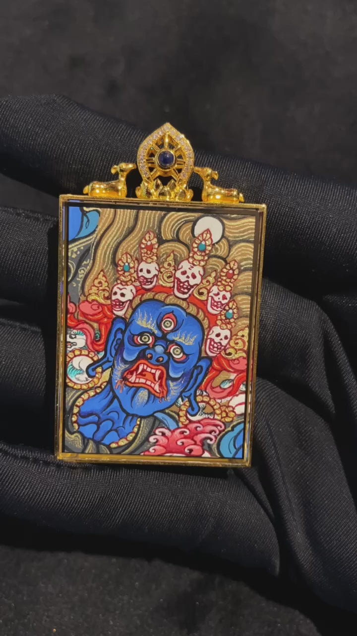 Close-up video of a double-sided Tibetan thangka pendant featuring Vajrasattva and Mahakala, fully hand-painted with 18K gold in the Rebgong tradition and encased in an 18K gold gau box with dual sapphire crystal mirrors, representing purification, root practice, and Dharma protection in Vajrayana Buddhism