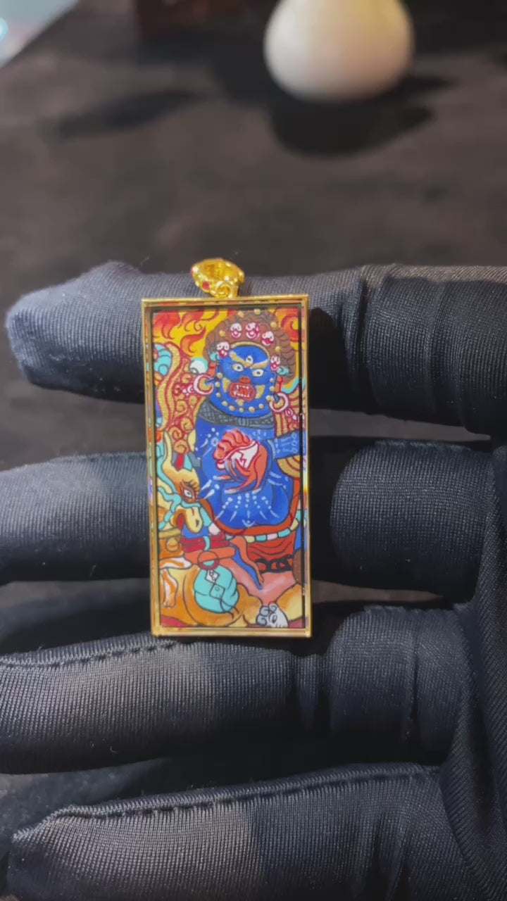 Close-up video of 18K gold double-sided hand-painted Mahakala thangka pendant, showing Rebgong full-work details, Gau box design, sapphire crystal, and mantra reverse