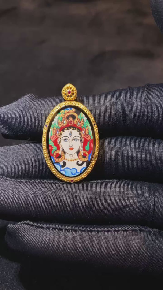 Close-up video of a White Tara Thangka pendant with mantra seed syllables, double-sided hand-painted in 18K gold, crafted in Rebgong style and set in a fully enclosed Gawu box